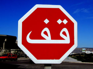znak drogowy z napisem stop w alfabecie arabskim