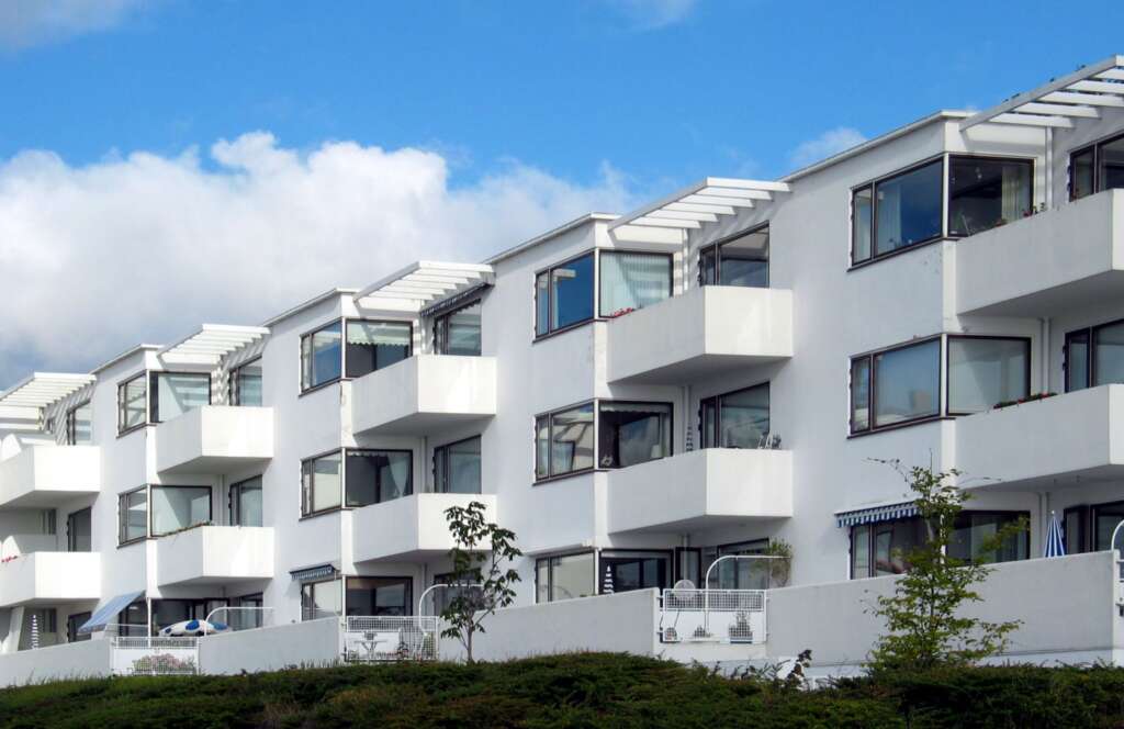 biały, wydłużony trzypiętrowy budynek z balkonami